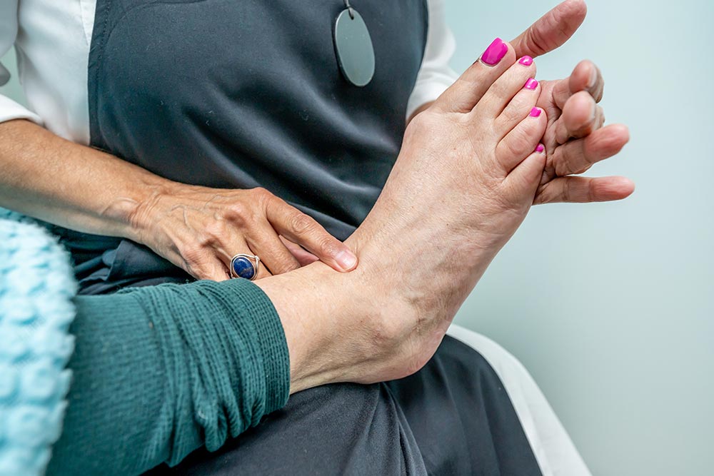 Bowen therapist gently applying pressure to woman's ankle