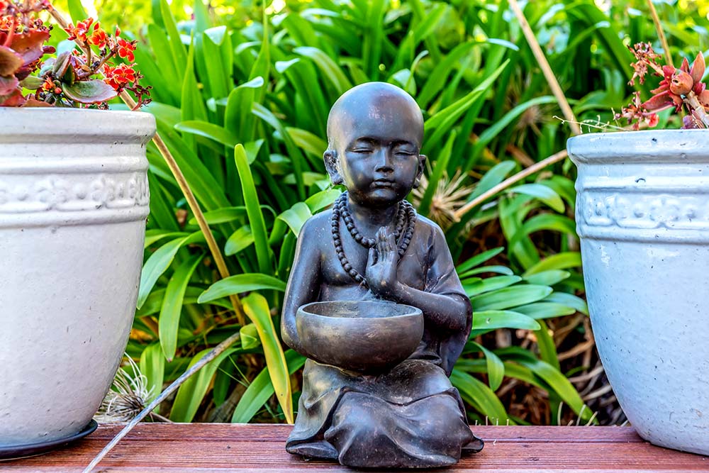 Dark grey small Buddha statue in garden
