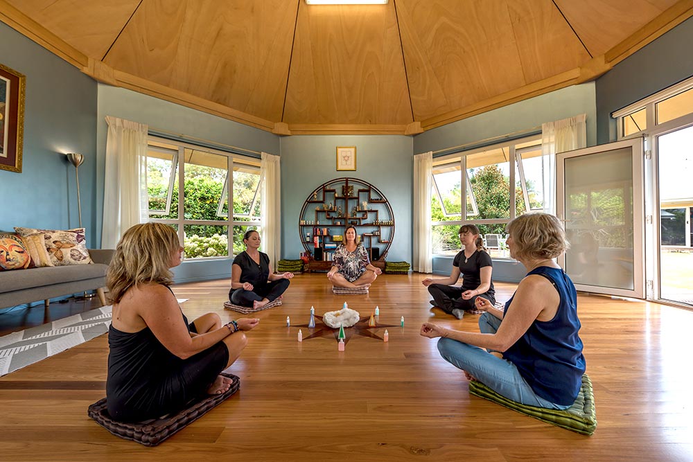 Women sitting on floor of octagonal room meditating